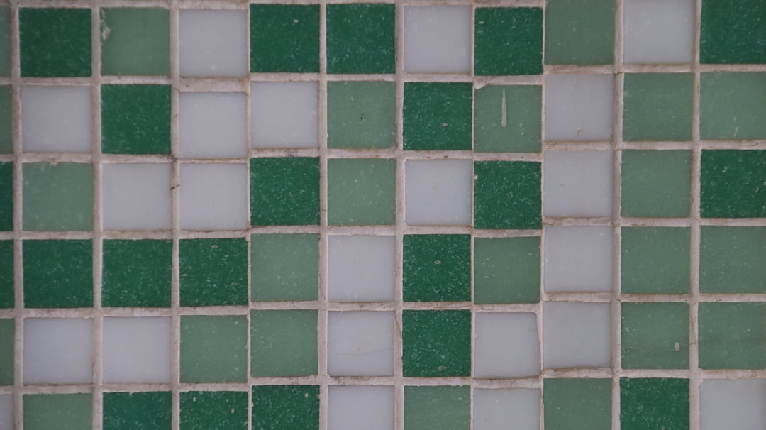 Insights 1 Close-up of a mosaic tile wall with alternating green and pale gray squares in a grid pattern.