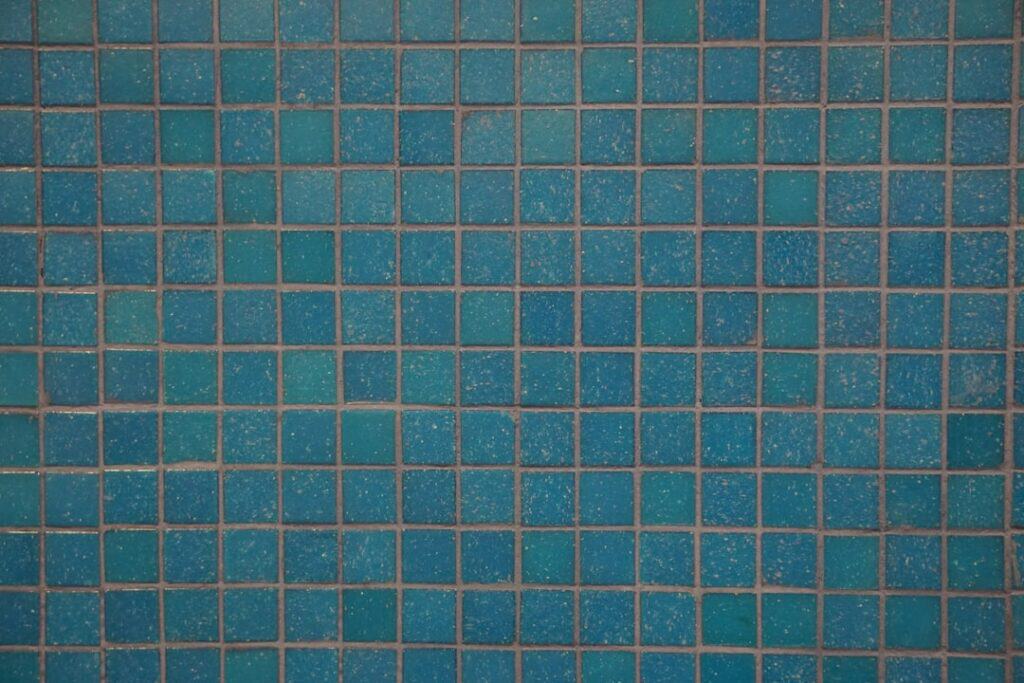 Blue square mosaic tiles arranged in a grid pattern on a wall.