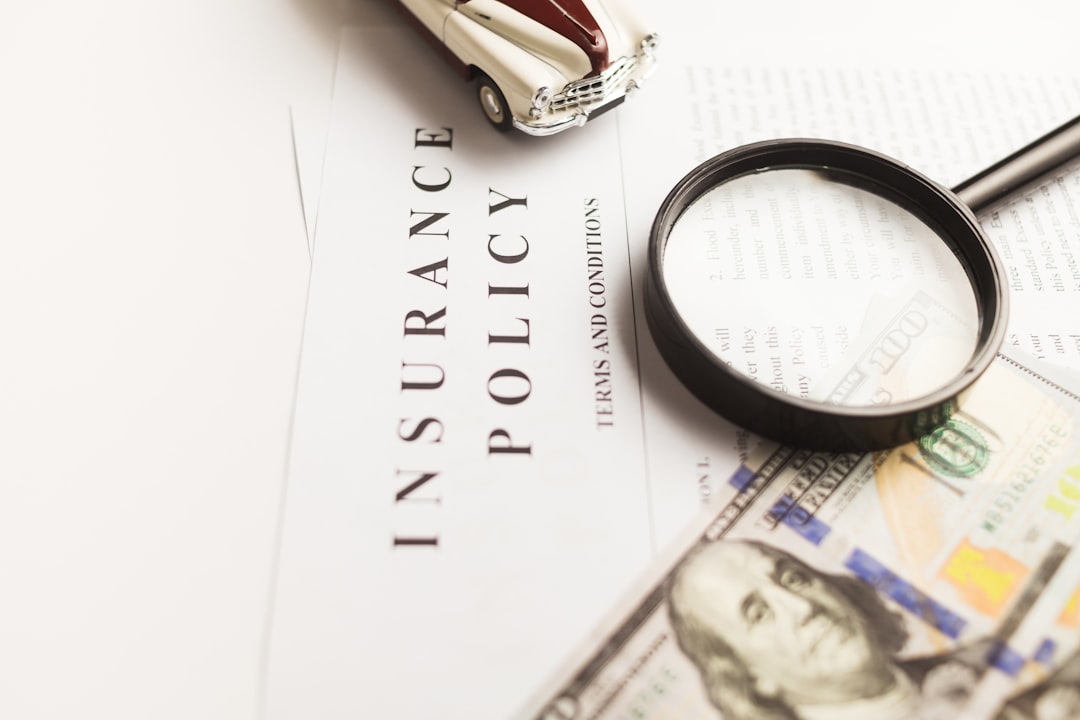 Insurance policy document with a magnifying glass, a miniature car, and scattered cash in the foreground.