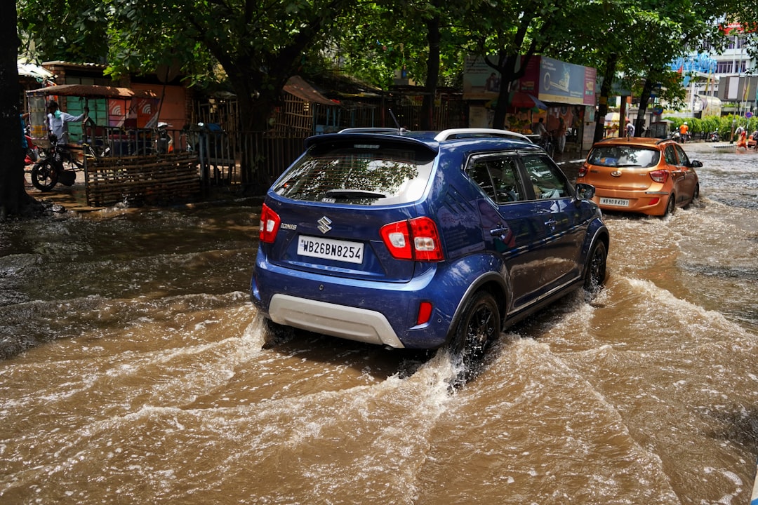Insights 2 Blue compact SUV driving through muddy floodwater on a busy street, with market stalls and pedestrians in the background.