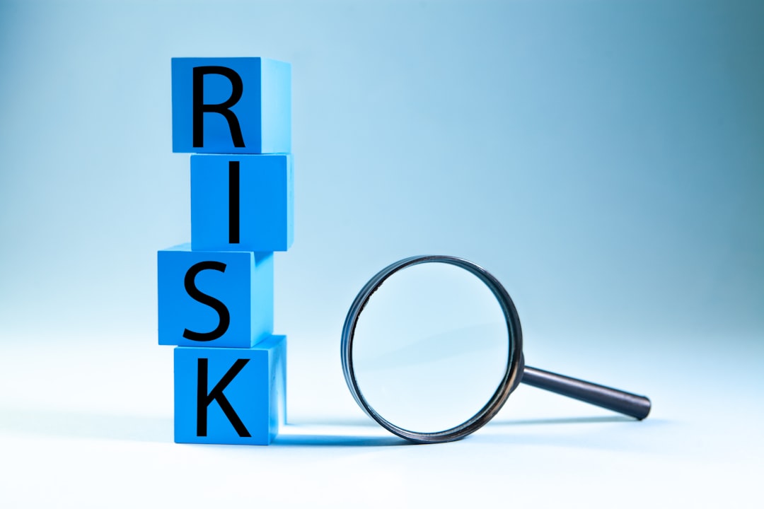 Blue cubes stacked to spell 'RISK' with a magnifying glass beside them, symbolizing risk assessment/analysis.